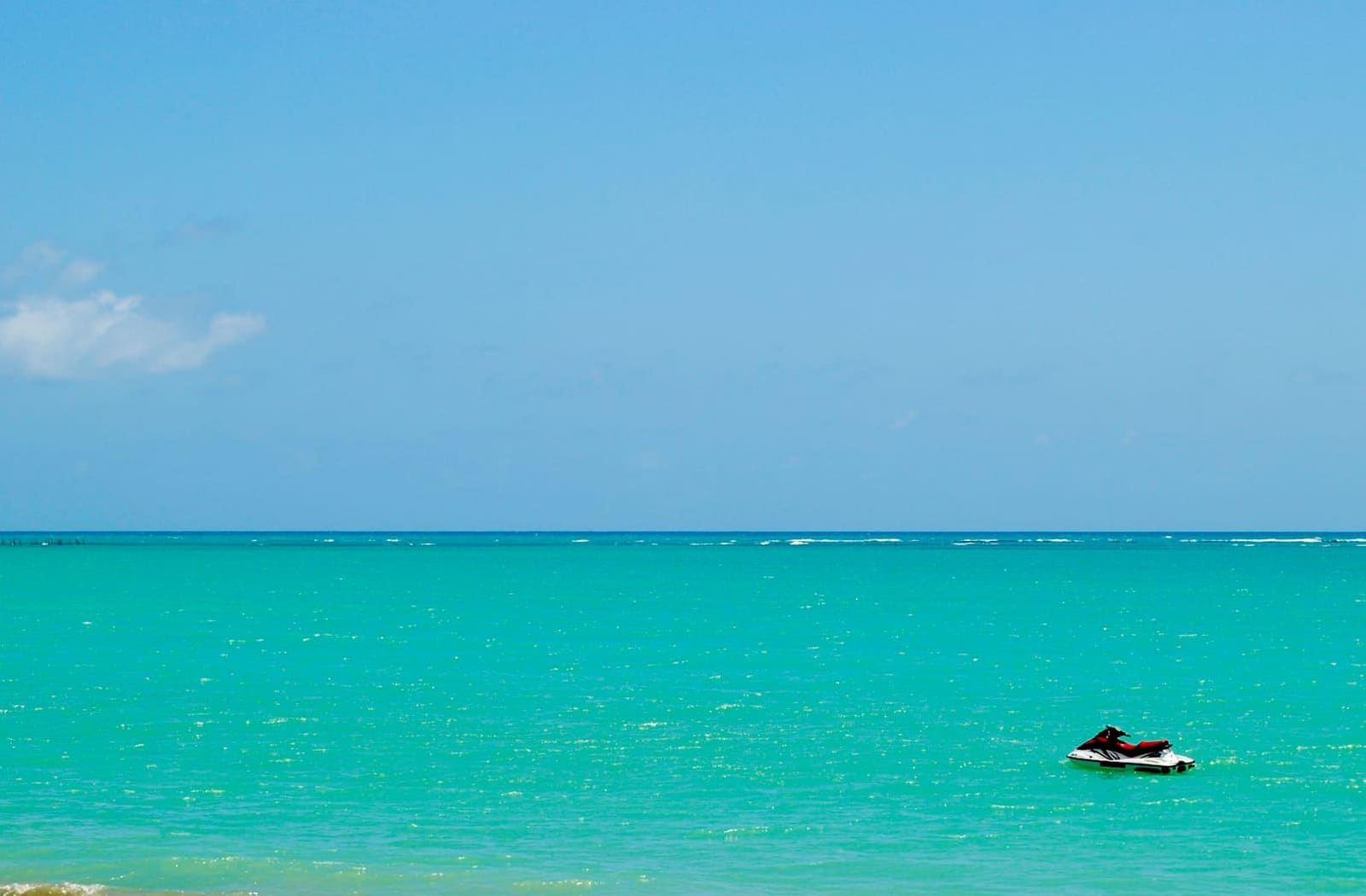 A distant jet ski on bright turquoise water