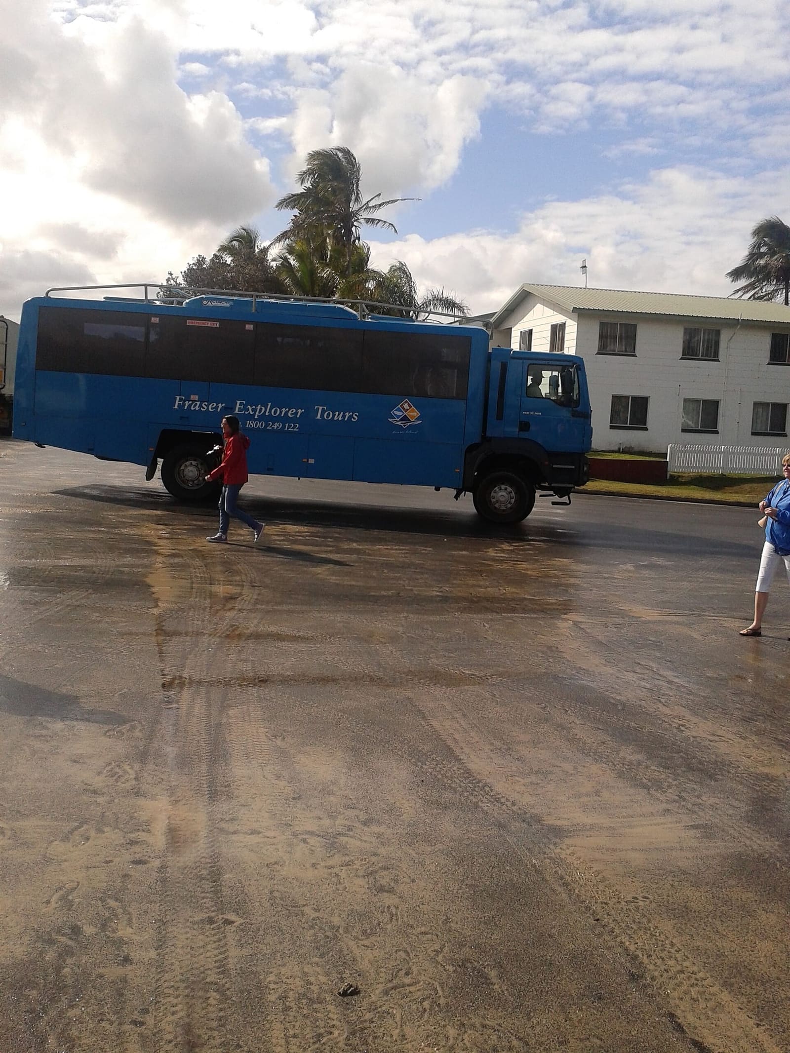 A branded 4WD tour bus on a sandy car park (illustrative; not identified as a K'gari Explorer coach)