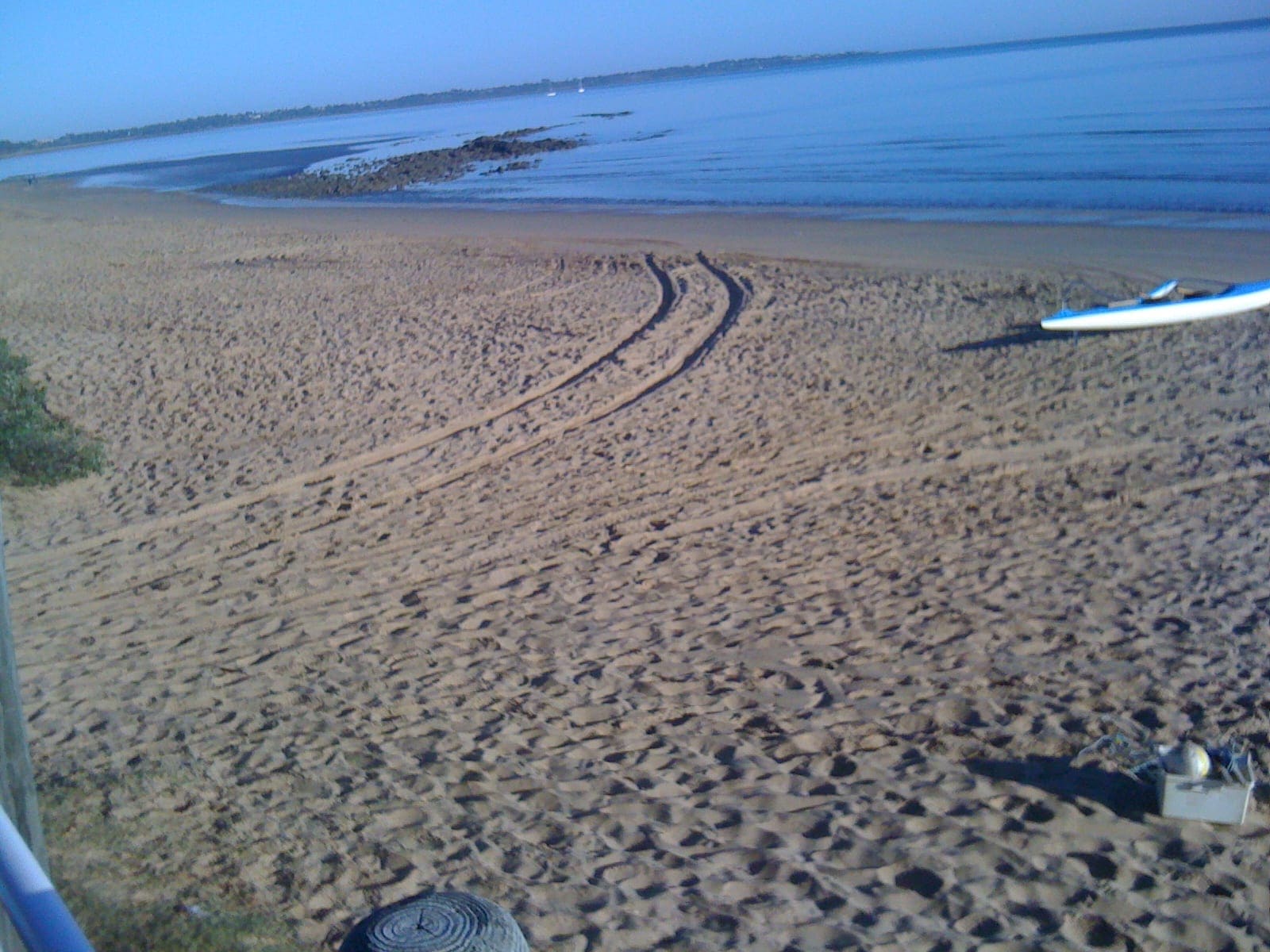 Torquay beach in Hervey Bay: tyre and foot tracks in the sand, a calm bay and a kayak at the water's edge